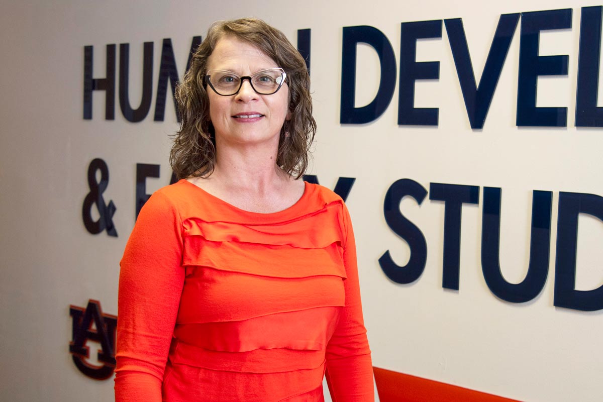 Photo of Angela standing in front of the HDFS wall graphic.