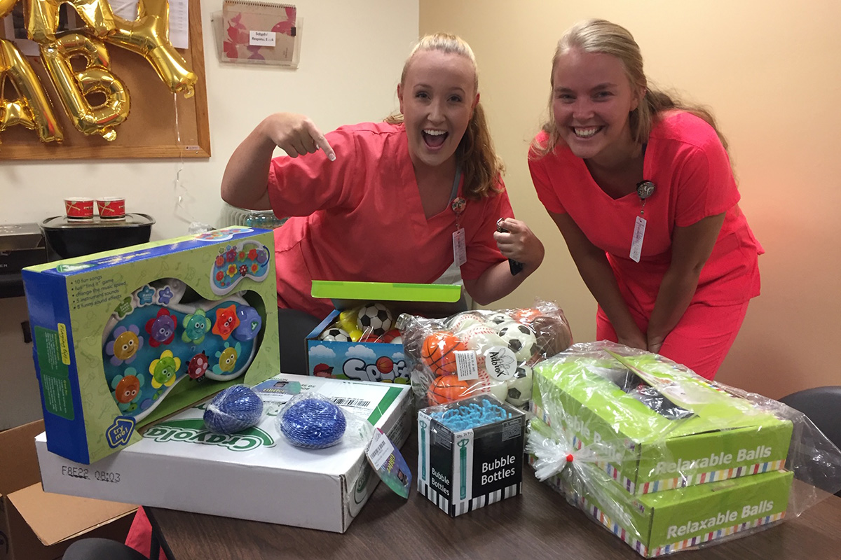 Students standing behind gifts on a table.